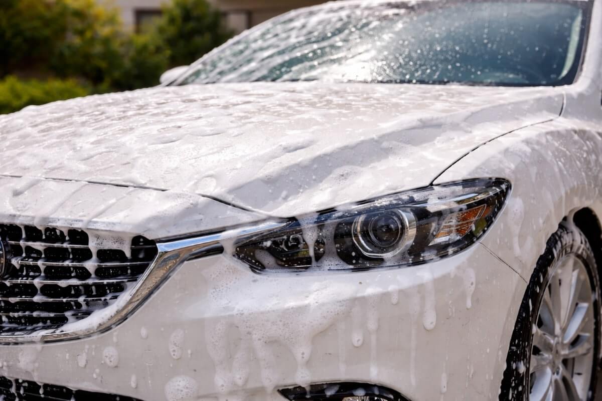 رغوة كثيفة من شامبو سيارات تغطي هيكل السيارة أثناء الغسيل المنزلي